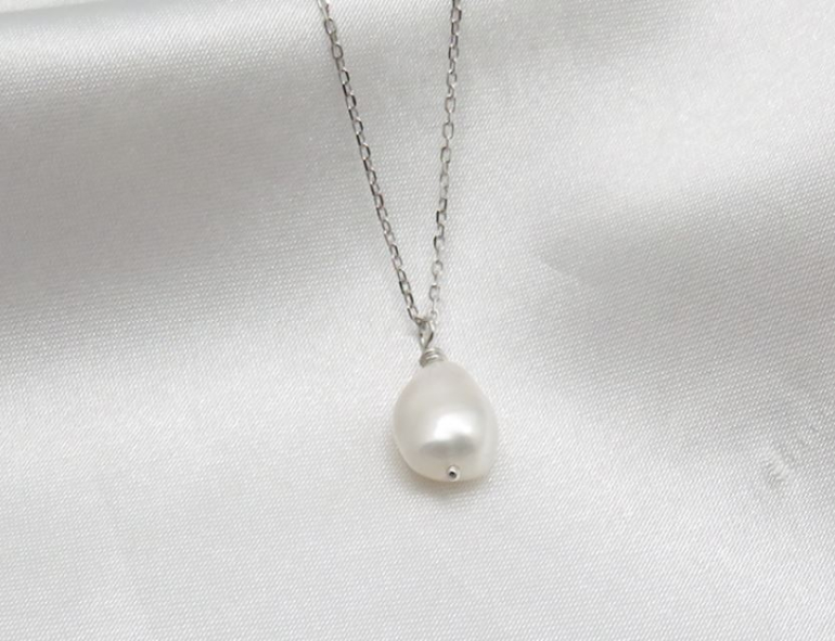 Sølvkæde med barok perle på hvid tekstil